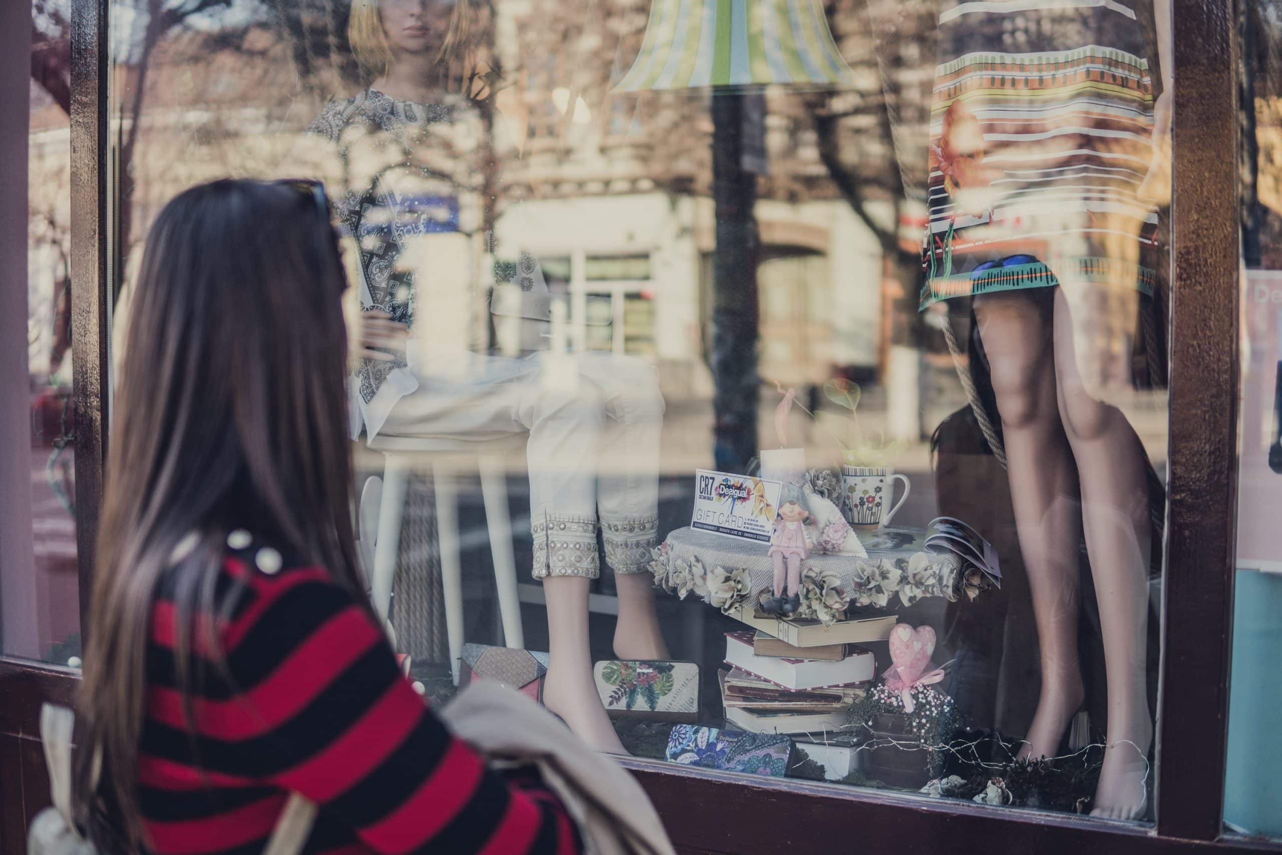 Femme regardant une vitrine de magasin de mode