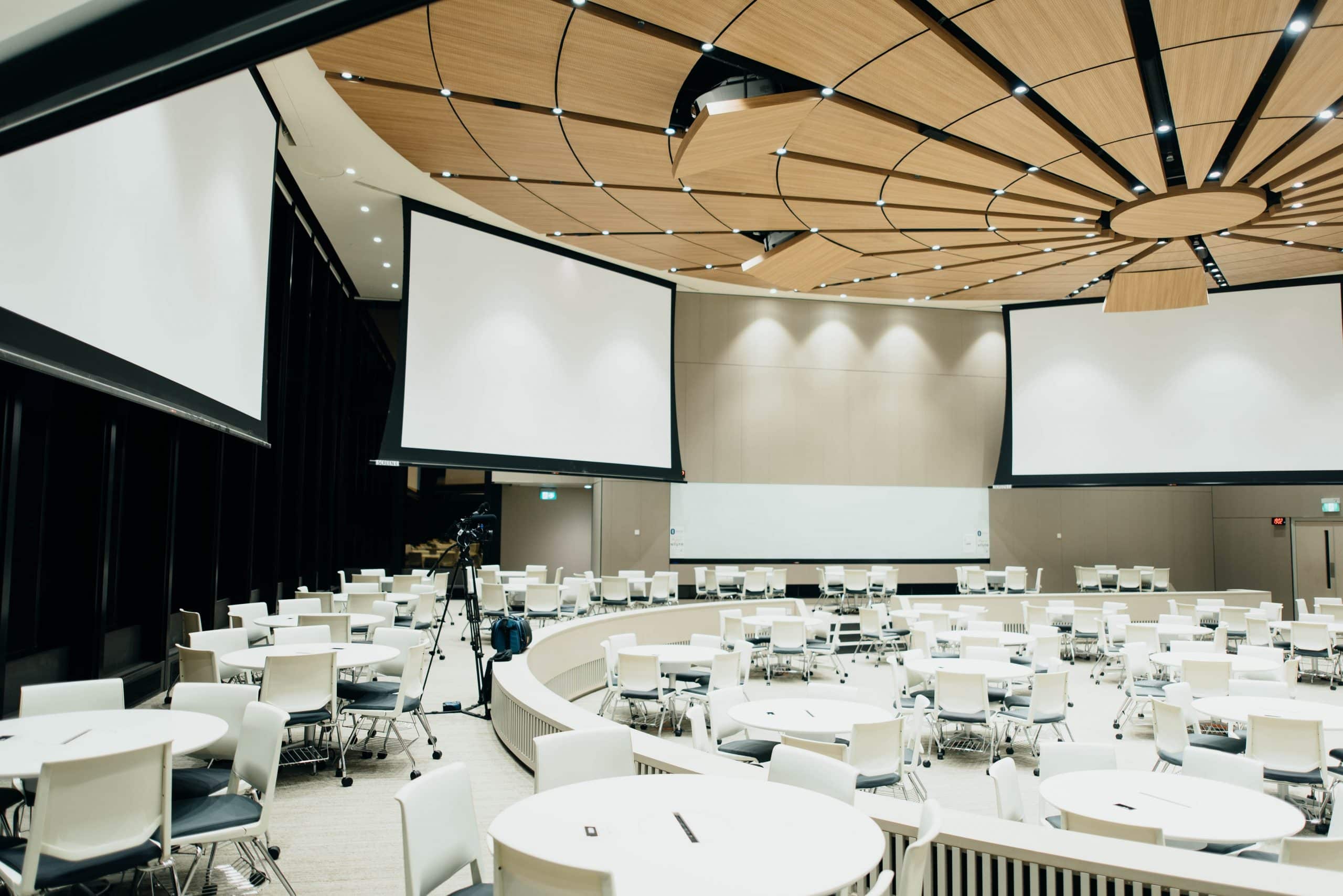 Grande salle avec des tables et des écrans pour un événement